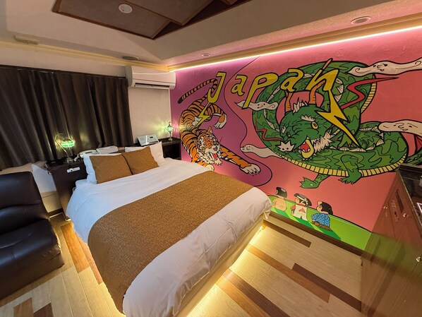 A hotel room with a bed, a nightstand, a lamp, and a wall mural.