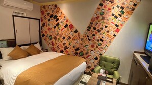 A hotel room with a bed, a green armchair, a small table with a remote control, and a wall with a pattern of food illustrations. - Sakura Osaka Castle North Hotel (Osaka)