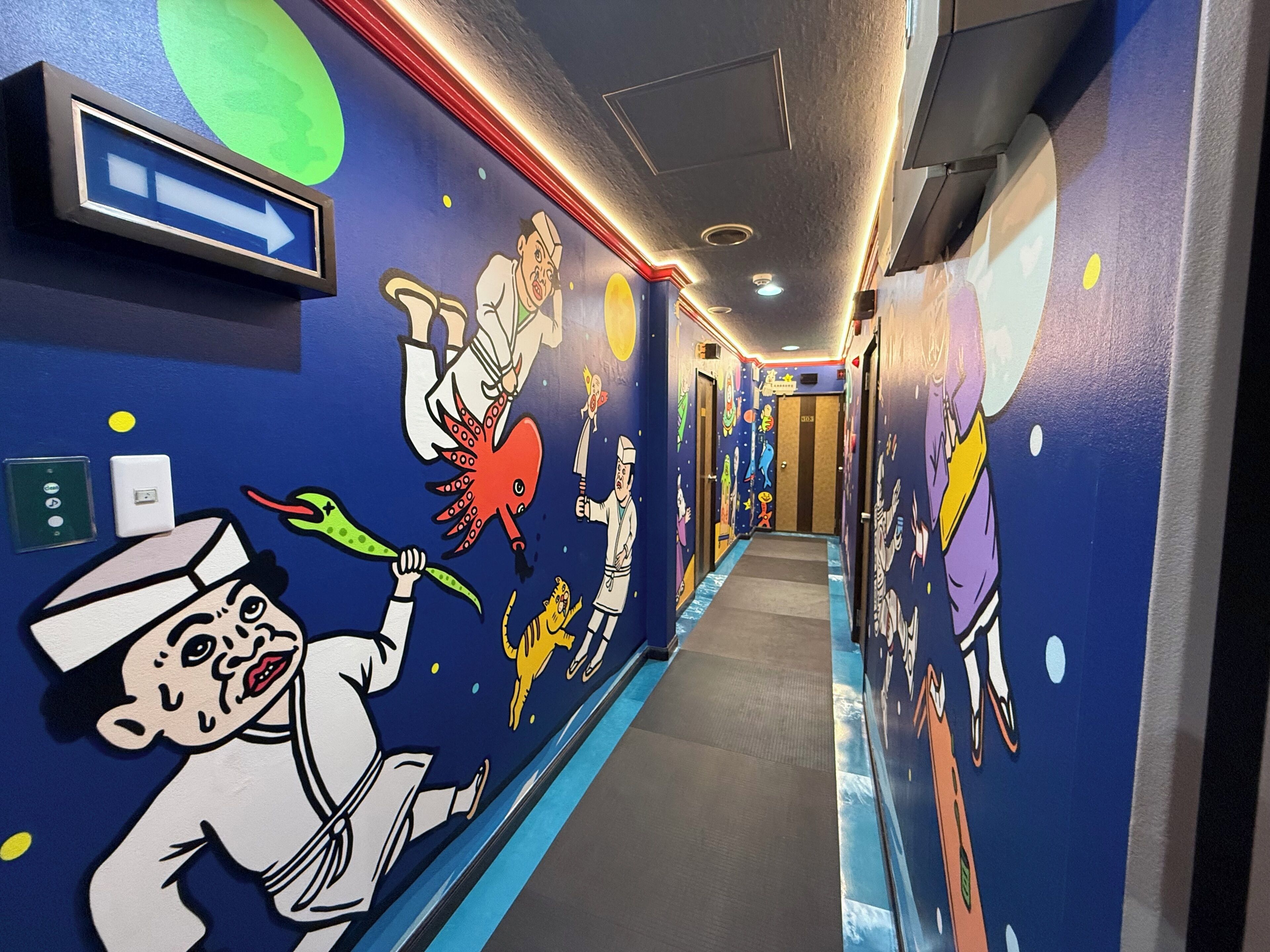 A hallway with colorful murals, a directional sign, and a door with the number 3103.