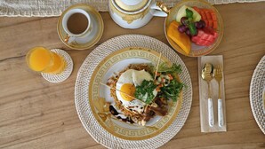 Ein Frühstückstisch mit Teller, Kaffeetasse und Glas Orangensaft.