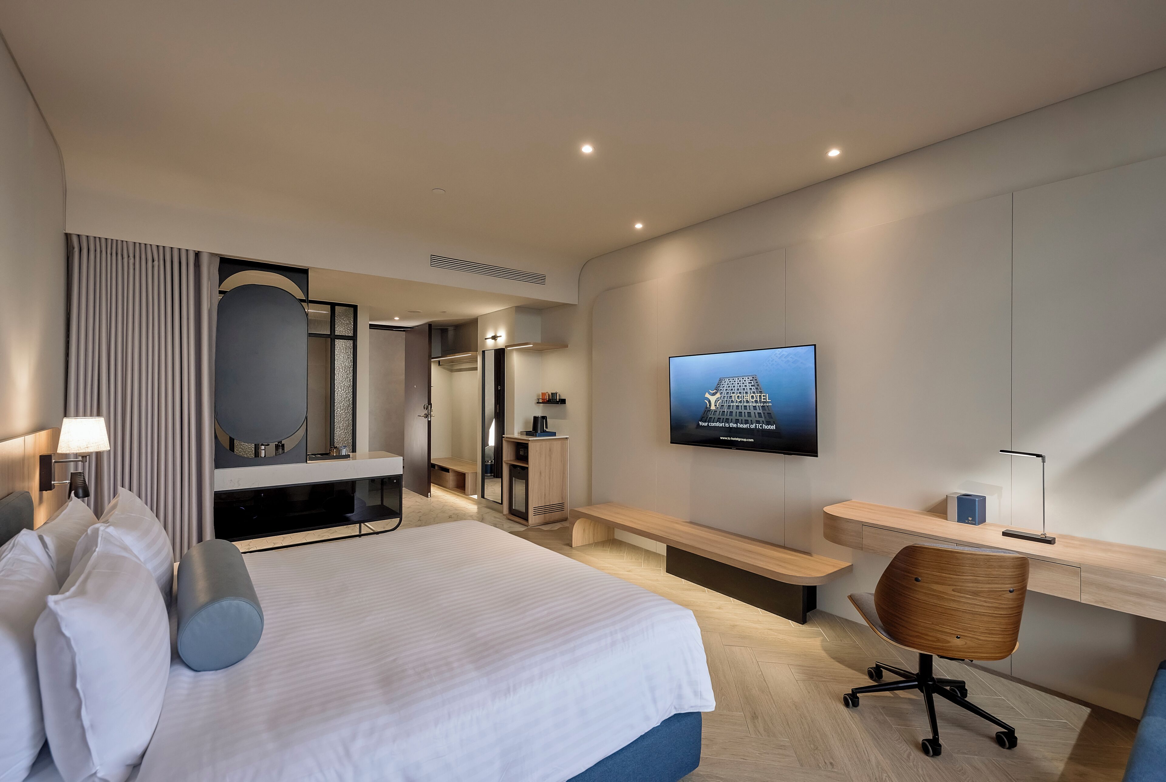 Een hotelkamer met een bed, een bureau, een stoel, een televisie en een spiegel.