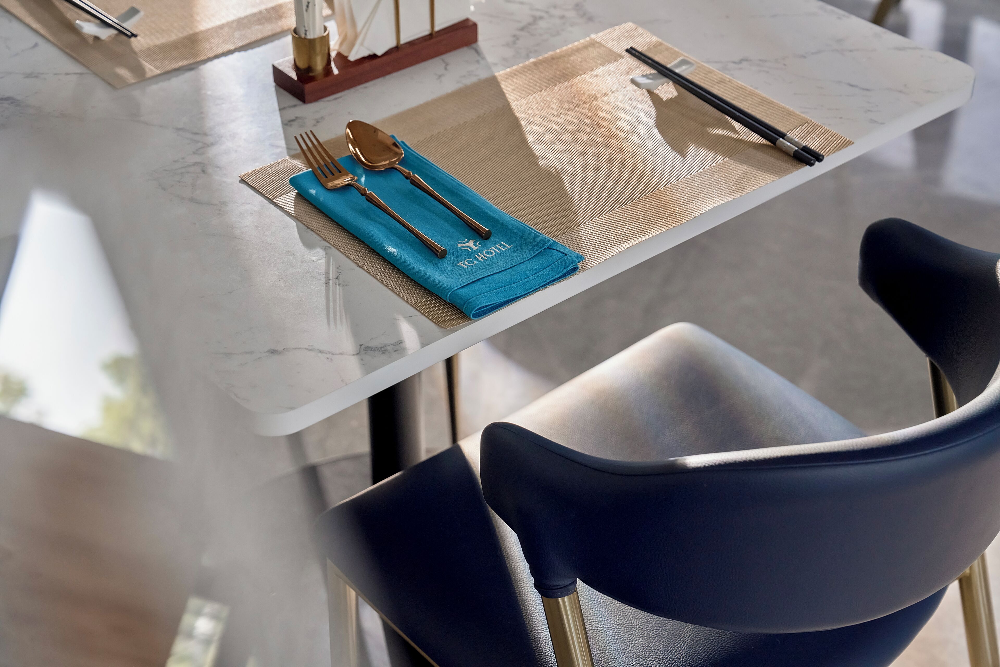 A dining table with a placemat, a folded napkin, and cutlery.