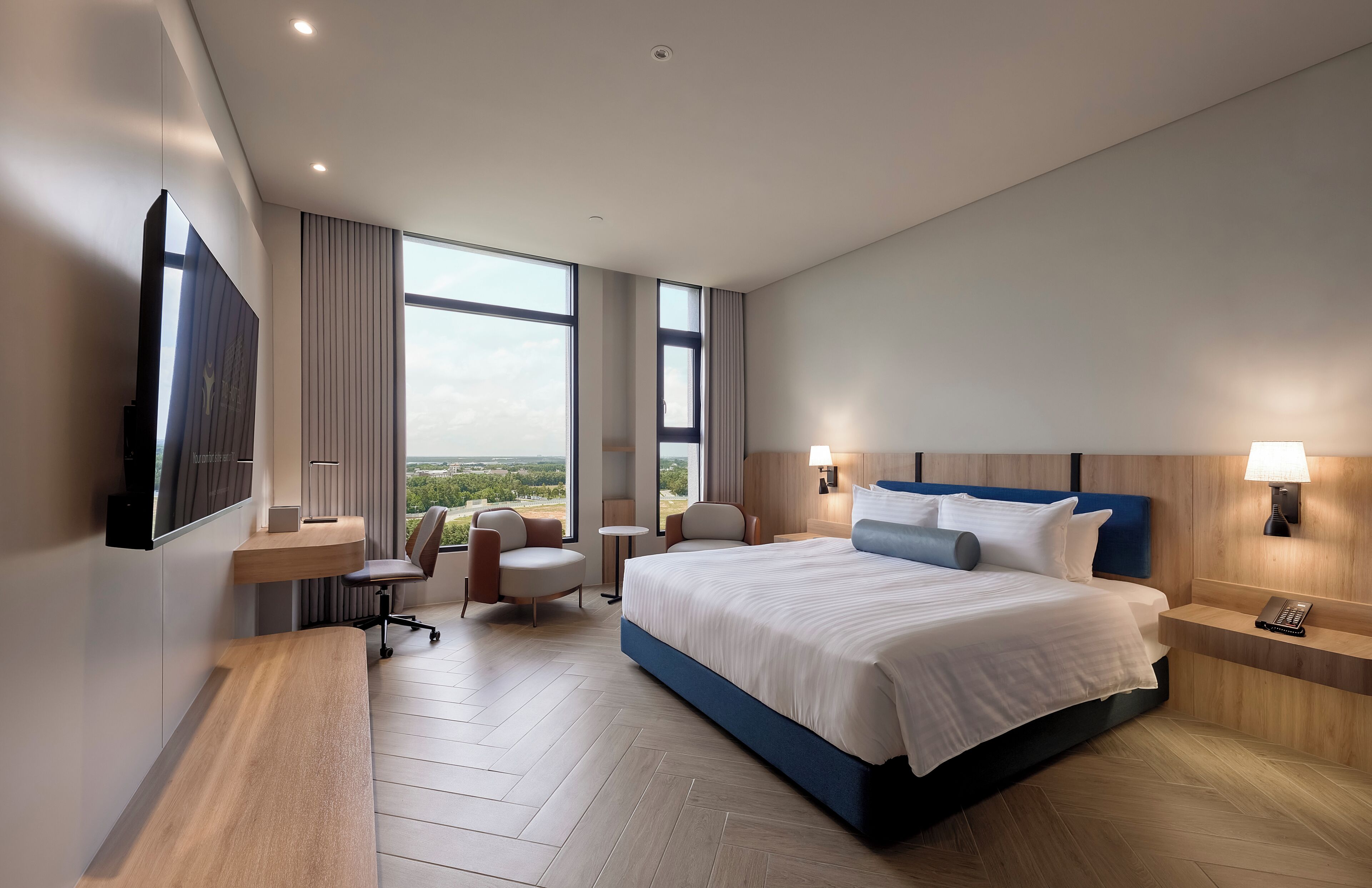 Una habitación de hotel moderna con una cama grande, un escritorio, una silla y vistas al exterior.