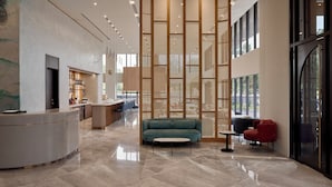 A spacious lobby with a reception desk, seating area, and a large window providing natural light.
