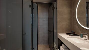 Un baño moderno con ducha envuelta en vidrio, tocador con espejo y suelo de mármol.