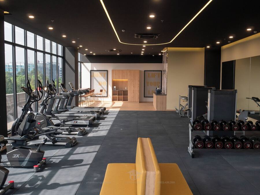 A gym with exercise equipment, a bench, and dumbbells.