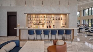 A modern bar area with a marble countertop, multiple bar stools, and a variety of bottles and glasses.
