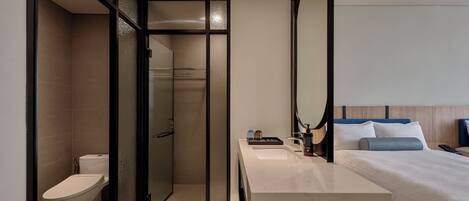 Una habitación de hotel moderna con ducha, inodoro y cama con mesita de noche.