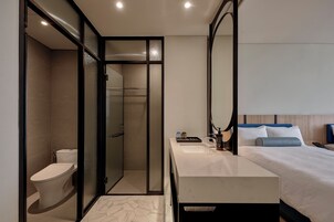 Una habitación de hotel moderna con ducha, inodoro y cama con mesita de noche.