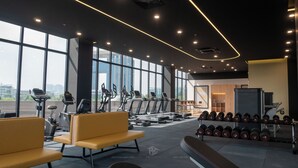 A gym with exercise equipment, weight benches, and dumbbells.