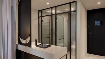 A modern bathroom with a large mirror, a white countertop, and frosted glass doors.