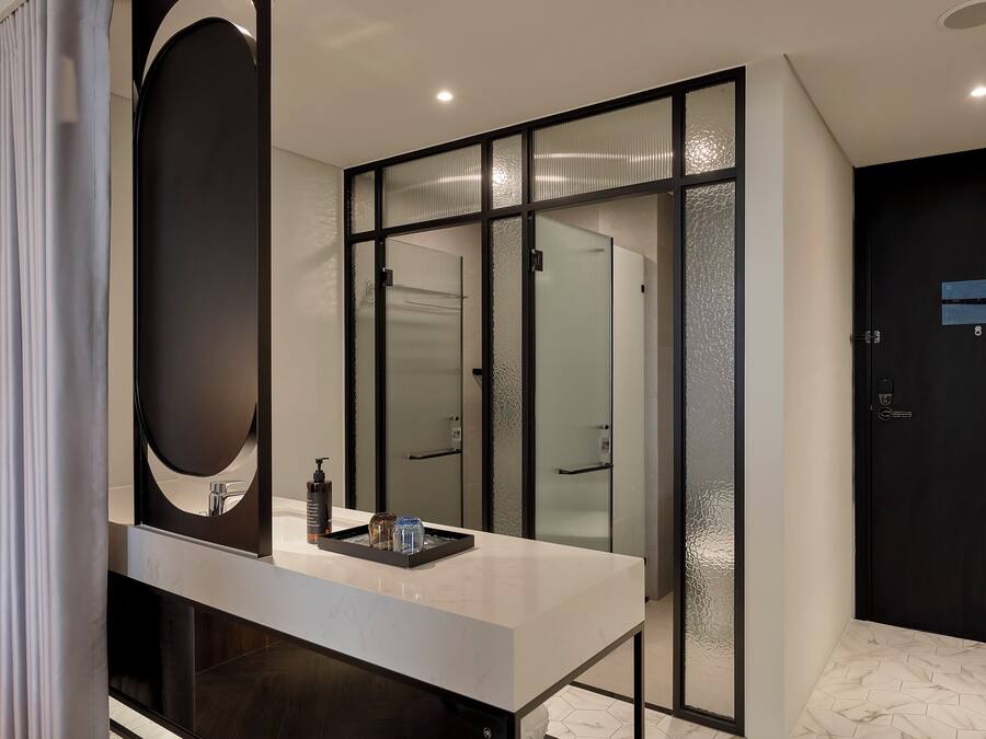 A modern bathroom with a large mirror, a white countertop, and frosted glass doors.