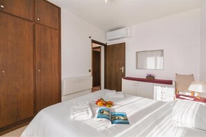 A hotel room with a large bed, a wooden wardrobe, a small bathroom with a mirror, and a radiator.