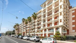 A multi-story building with balconies, parked cars, and palm trees. - Admiral Plaza Sea View, Menton, France (Menton)