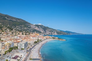 Eine Küstenstadt mit Strand, Gebäuden und einem Berg im Hintergrund.