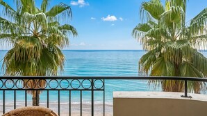 A balcony with a view of the sea, palm trees, and a wicker chair. - Admiral Plaza Sea View, Menton, France (Menton)