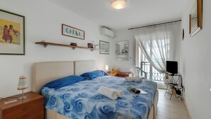 A bedroom with a bed, bedside tables, a TV, and a window with curtains. - Admiral Plaza Sea View, Menton, France (Menton)