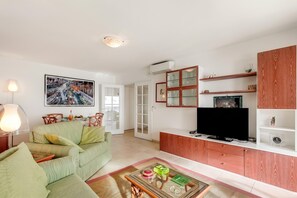 A living room with a sofa, a coffee table, a television, and a cabinet.
