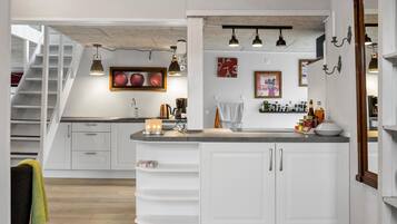 A modern kitchen with a central island, white cabinetry, and a staircase leading to an upper level.