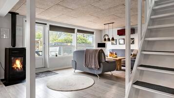 A modern living room with a fireplace, a grey sofa, a round rug, and a staircase.