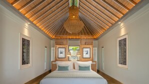A spacious bedroom with a large bed, a wooden ceiling, and framed artwork on the walls. - Sudamala Resort Ubud Bali (Ubud)