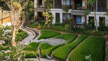A modern hotel with multiple balconies, a landscaped garden with terraced greenery, and a clear view of the surrounding natural environment.