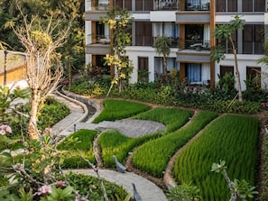 A modern hotel with multiple balconies, a landscaped garden with terraced greenery, and a clear view of the surrounding natural environment. - Sudamala Resort Ubud Bali (Ubud)