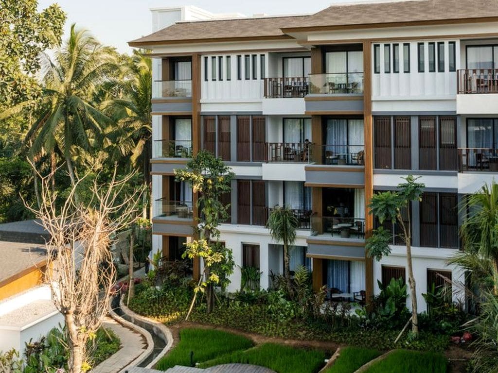 Un hôtel à plusieurs étages doté de balcons, d’un jardin et d’un sentier.