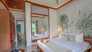Een slaapkamer met een groot bed, een houten hoofdbord, een nachtkastje met een lamp en een spiegel. Er is uitzicht op een badkamer en een gang met een houten deur.