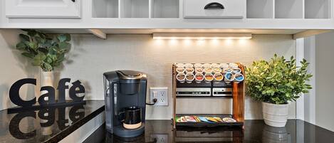 Una cocina con armarios blancos, una cafetera, un estante para especias y una planta en maceta.