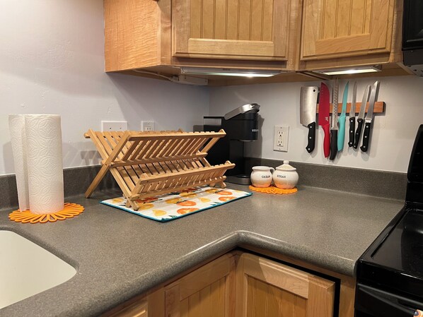 A kitchen with wooden cabinets, a coffee maker, a knife rack, and two containers labeled "cream" and "sugar".