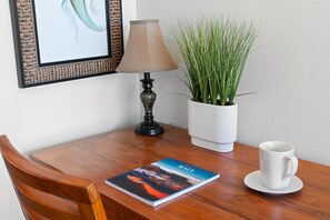 A wooden table with a book, a white mug, a lamp, and a potted plant.
