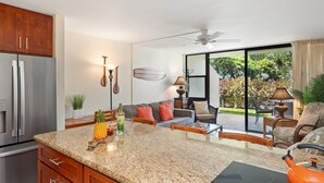 A kitchen with granite countertops, a refrigerator, and a dining area with a table and chairs.