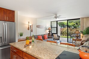 Una cocina con encimeras de granito, un refrigerador y un comedor con mesa y sillas.