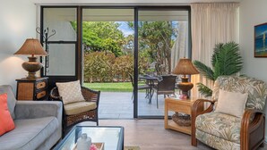A living room with a sofa, armchairs, a coffee table, and a dining area with chairs and a table.