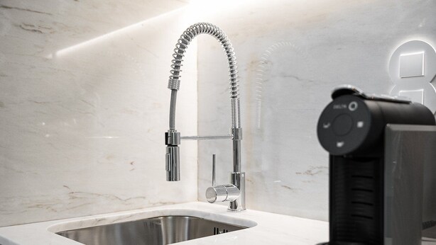 A modern kitchen with a stainless steel sink, a flexible faucet, and a built-in coffee machine.