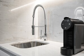 A modern kitchen with a stainless steel sink, a flexible faucet, and a built-in coffee machine.