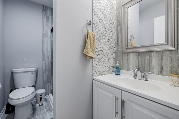Un baño con inodoro, bidé y lavabo con espejo superior.