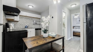 Una cocina moderna con armarios blancos, una campana extractora negra y una mesa de madera con un florero de orquídea blanca.