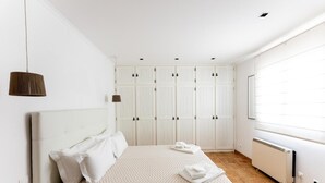 A bedroom with a bed, white wardrobe, and a radiator.