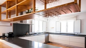 A modern kitchen with a black countertop, white cabinets, and a wooden ceiling structure.