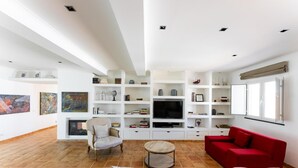 A modern living room with a fireplace, a television, and a red sofa.