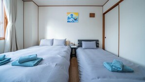 A hotel room with two beds, a painting on the wall, and a small table between the beds. - YADOKITO 1 201 (Otaru)