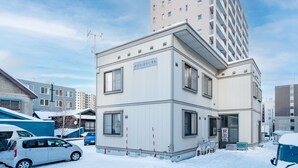 A modern building with a flat roof, large windows, and a sign indicating it is a hotel. - YADOKITO 1 201 (Otaru)