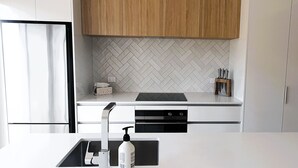 Et moderne køkken med lyse skabe, et backsplash af fiskebensmønstrede fliser og en bordplade i sort farve.