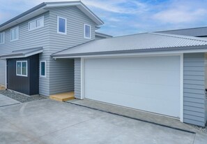 A two-story house with a garage and a covered entryway. - Peace in Paradise (Taupō)