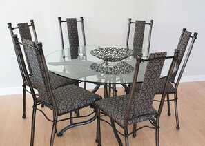 A round glass table with a patterned metal frame, surrounded by six chairs with patterned upholstery. - Peace in Paradise (Taupō)