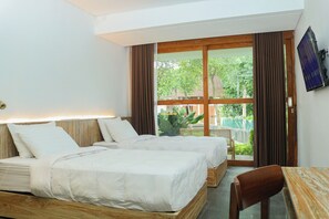 Une chambre d’hôtel avec deux lits, une tête de lit en bois, une table et un téléviseur fixé au mur.