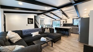 A modern living room with a sofa, coffee table, and a view of the kitchen.
