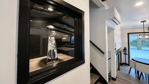 A modern interior with a trophy on a shelf, a staircase, and a dining area with a view.